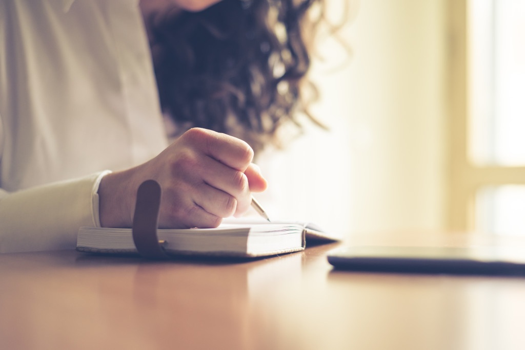 beautiful woman at home writing and working with diary and smart phone
