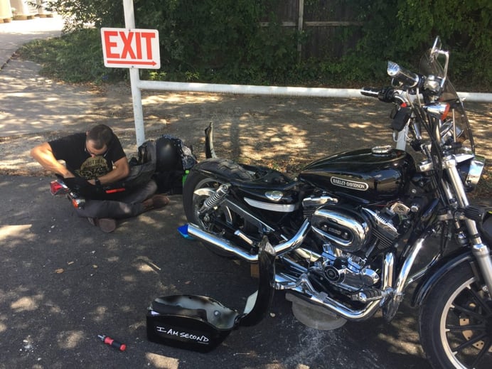 My brother-in-law, who is a mechanic, works on my bike during one of the many times it broke down. (Photo source: Jonathon M. Seidl)